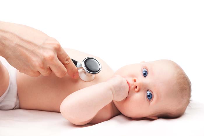 nahaufnahme eines babys bzw kindes. es wird von einem kardiologen mit dem stethoskop am herzen untersucht